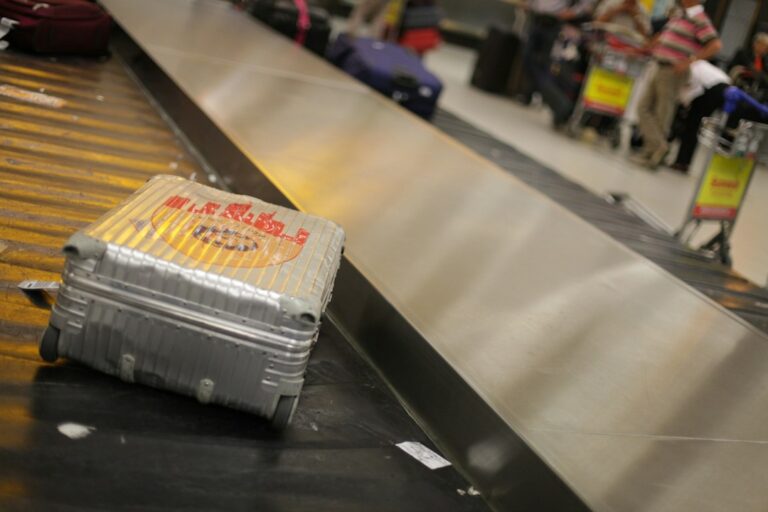 Traveler reports a missing suitcase at an airport baggage counter while holding a baggage claim ticket.